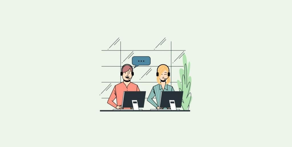Two people sitting at a desk at a computer, discussing strategies for building a customer service team.